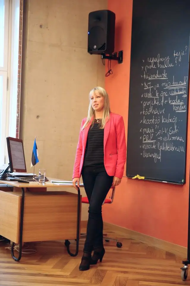 Svetlana Ambre стоит в учебном классе на фоне доски во время урока